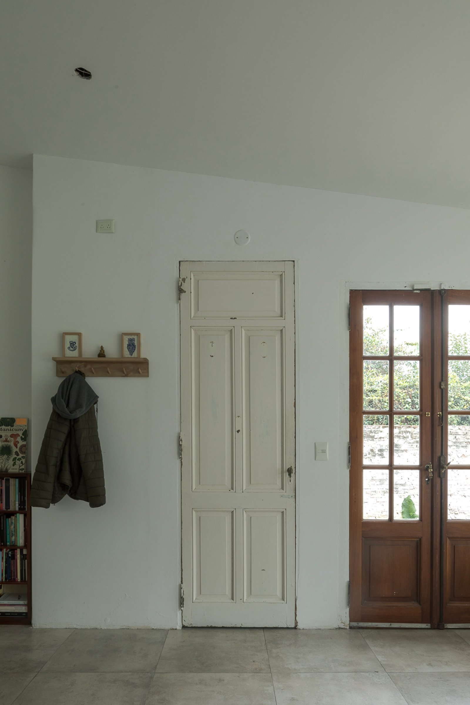 Corredor com porta dupla branca e porta de vidro em madeira — projeto Reforma Navarro, por Estudio YME, em B1648 Tigre